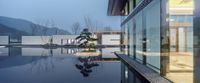 the interior of a modern house with a water view at twilight from an indoor pool