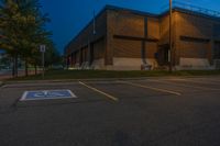 parking lot lit up with the light from an open window at twilight as seen from outside