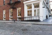 two cats and an umbrella are sitting on the sidewalk in front of a building with doors