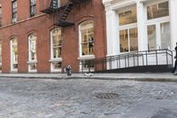 two cats and an umbrella are sitting on the sidewalk in front of a building with doors