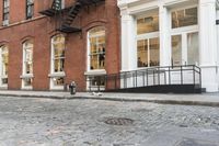 two cats and an umbrella are sitting on the sidewalk in front of a building with doors