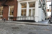 two cats and an umbrella are sitting on the sidewalk in front of a building with doors