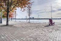 two park chairs sit on the side of the water by the river shore in fall