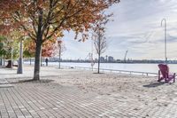 two park chairs sit on the side of the water by the river shore in fall