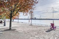 two park chairs sit on the side of the water by the river shore in fall