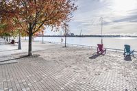 two park chairs sit on the side of the water by the river shore in fall