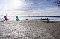 two park chairs sit on the side of the water by the river shore in fall