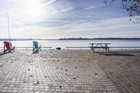 two park chairs sit on the side of the water by the river shore in fall