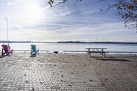 two park chairs sit on the side of the water by the river shore in fall