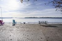 two park chairs sit on the side of the water by the river shore in fall