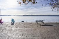 two park chairs sit on the side of the water by the river shore in fall