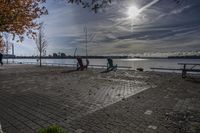 two park chairs sit on the side of the water by the river shore in fall