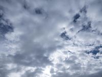 two men fly a kite on the beach during day time with low clouds overhead overhead