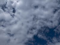 two men fly a kite on the beach during day time with low clouds overhead overhead