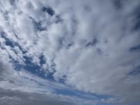 two men fly a kite on the beach during day time with low clouds overhead overhead