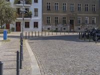 two men are walking down the cobblestone street with scooters and mopeds