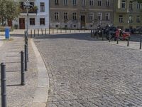 two men are walking down the cobblestone street with scooters and mopeds