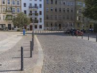 two men are walking down the cobblestone street with scooters and mopeds