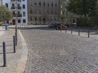 two men are walking down the cobblestone street with scooters and mopeds