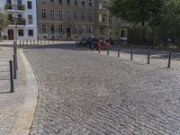 two men are walking down the cobblestone street with scooters and mopeds