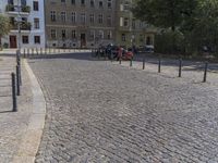 two men are walking down the cobblestone street with scooters and mopeds