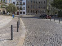 two men are walking down the cobblestone street with scooters and mopeds