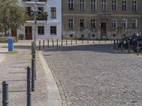 two men are walking down the cobblestone street with scooters and mopeds