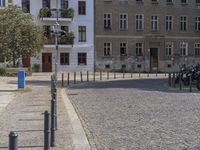 two men are walking down the cobblestone street with scooters and mopeds