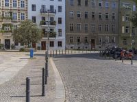 two men are walking down the cobblestone street with scooters and mopeds