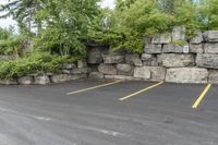 two parking spaces with yellow line markings next to rock wall in a residential neighborhood area