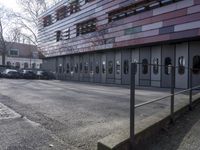two people standing in front of a glass building on a brick walkway between two rows of doors
