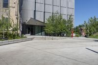 two people holding skateboards standing in an open courtyard space near buildings and a statue