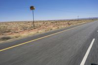 two people riding their bikes down the middle of an empty road in a desert landscape