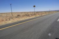 two people riding their bikes down the middle of an empty road in a desert landscape