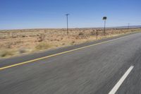 two people riding their bikes down the middle of an empty road in a desert landscape