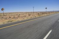 two people riding their bikes down the middle of an empty road in a desert landscape