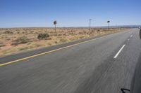 two people riding their bikes down the middle of an empty road in a desert landscape