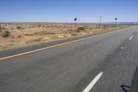 two people riding their bikes down the middle of an empty road in a desert landscape