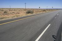 two people riding their bikes down the middle of an empty road in a desert landscape