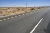 two people riding their bikes down the middle of an empty road in a desert landscape