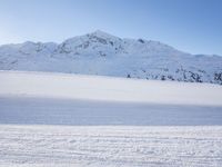 two people riding skis on snow covered ground next to mountains side by side,