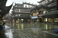 two people walking in the rain on a city street near a building with two towers