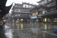 two people walking in the rain on a city street near a building with two towers