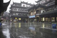 two people walking in the rain on a city street near a building with two towers