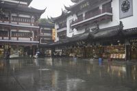 two people walking in the rain on a city street near a building with two towers