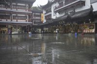 two people walking in the rain on a city street near a building with two towers