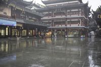 two people walking in the rain on a city street near a building with two towers