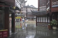 two people walking in the rain on a city street near a building with two towers