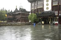 two people walking in the rain on a city street near a building with two towers