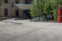 two red post meters with no people at them on a paved sidewalk outside a brick building